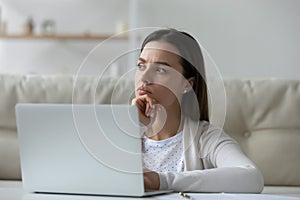 Pensive girl sit in front of laptop thinking over task