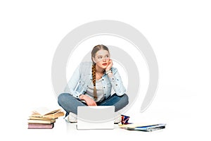 Pensive girl sitting on floor with laptop, books and copybooks and holding uk flag