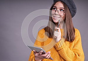 Pensive girl student with pen and tablet smiling