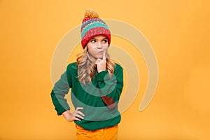 Pensive girl in sweater and hat with arm on hip