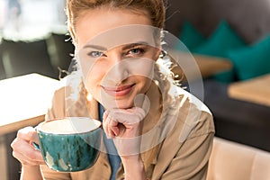 Pensive girl tasting mug of hot beverage