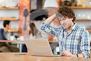 Pensive guy thinking and using laptop in cafe