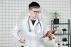 Pensive handsome young male doctor using tablet computer. Technologies in medicine concept