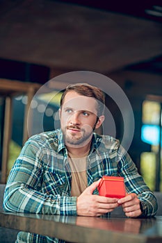 Pensive happy man with gift in cafe