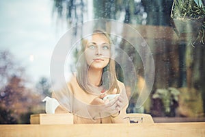 Pensive happy woman remembering looking at side sitting in a bar, coffeee shop