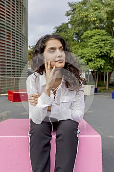 Pensive happy woman remembering looking at side sitting outdoors