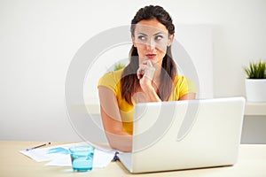 Pensive hispanic employee working on her laptop