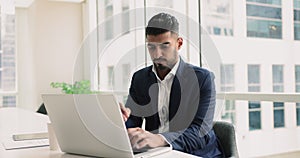 Pensive Indian businessman using laptop in office