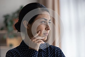 Pensive Indian woman look in distance thinking