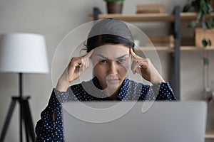 Pensive Indian woman look at laptop thinking