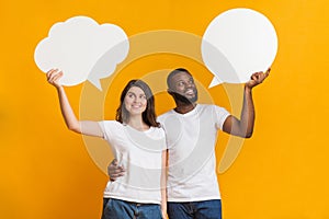 Pensive interracial couple holding empty speech bubbles above their heads