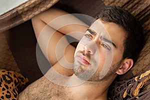 Pensive Italian Brazilian young man laying in a hammock, unedited skin