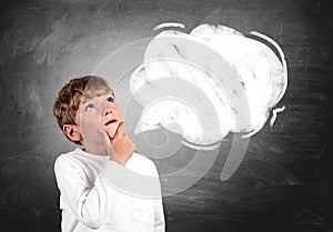 Pensive kid boy portrait looking up, chalkboard with empty speech bubble