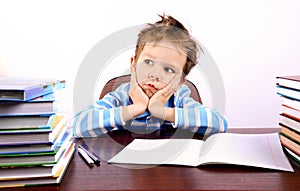 Pensive little boy sitting at a desk