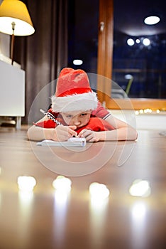 Pensive little boy writing a letter to Santa Claus