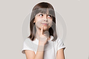 Pensive little girl hold finger on chin isolated on beige