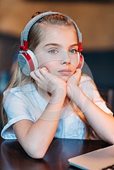 Pensive little girl listening music in headphones