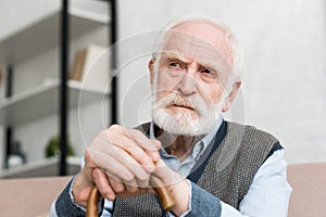 Pensive and lonely grey haired man with walking stick