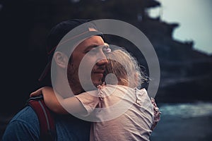 Pensive lonely man father holding child daughter looking with hope into distance in dark vintage style