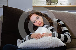 Pensive and lonely young woman relaxing on a sofa