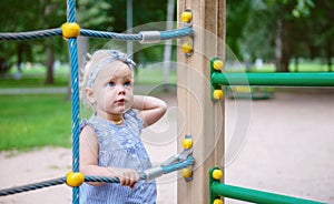 Pensive look of a child in front of a rope net on a playground