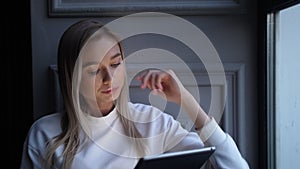 Pensive looking lady portraits. Person holds tablet computer, touches screen.