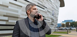 pensive male architect speaks on the phone on the background of the building