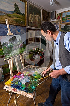 Pensive male artist mixing colors in a gallery