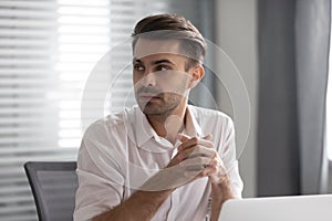 Pensive male employee look to side listen to coworker talk photo