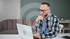 Pensive male freelancer thinking looking laptop sitting on desk. Shot on RED Raven 4k Cinema Camera