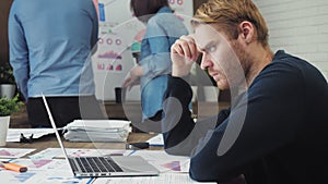 Pensive male office worker looking at computer screen with data