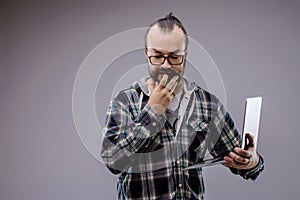 Pensive male web developer thinking and holding laptop