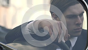 Pensive man in a 1920s suit sitting at the wheel, close-up shooting