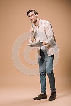 Pensive man in glasses holding notebook and pen