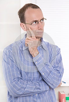Pensive man with glasses touching chin.