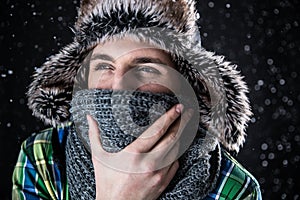 Pensive man in hat and scarf with snow