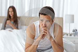 Pensive man having a headache sitting on the bed