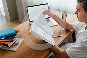 Pensive man at home while remote learning using laptop