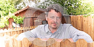 Pensive man outdoor in garden with wood hut home background