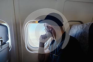 A pensive man sits at the window on an airplane