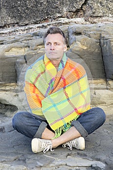 Pensive man sitting on a rock alone.