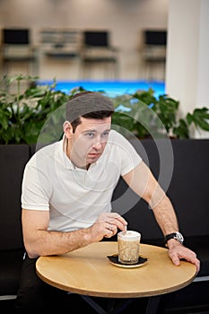 Pensive man in white shirt sits at round table photo