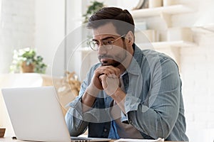 Pensive man work at laptop at home thinking