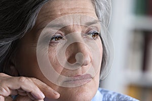 Pensive mature grey haired lady looking away in deep thought