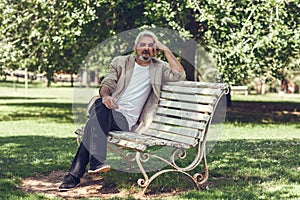 Pensive mature man sitting on bench in an urban park.
