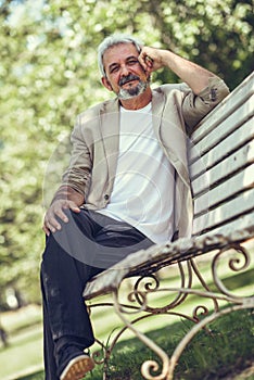 Pensive mature man sitting on bench in an urban park.