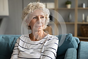 Pensive mature woman look in distance feeling lonely