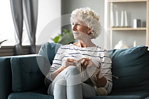 Pensive mature woman relax in living room knitting