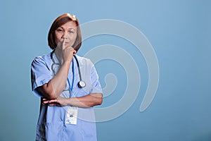 Pensive medical assistant wearing blue uniform thinking about health care treatment