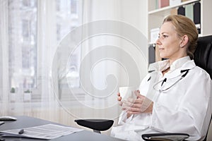 Pensive Medical Doctor with Drink Sitting on Chair